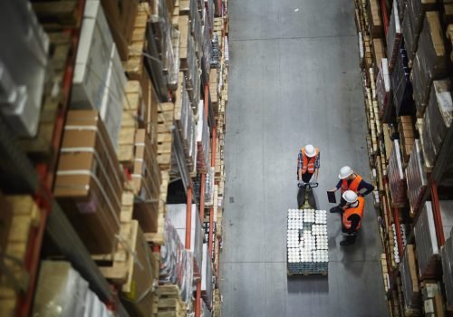 Group of workers in uniform and helmets having talk in aisle