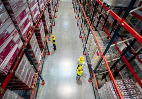 Warehouse managers consult plans using laptop, above view